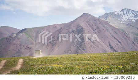 Old army truck heading towards mountains on a dusty road, Pamir mountains, Kyrgyzstan Old army truck heading towards mountains on a dusty road, Pamir mountains, Kyrgyzstan 123009286