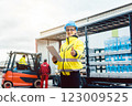 woman in front of forklift transporting goods from warehouse 123009525