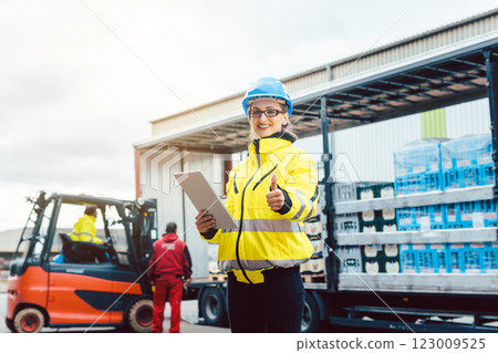 woman in front of forklift transporting goods from warehouse 123009525
