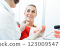 Female dentist explaining artificial teeth to her patient in clinic 123009547