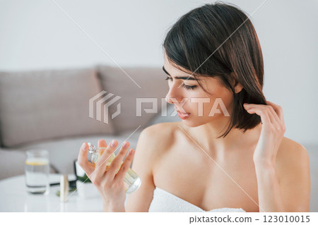 Trying new parfume. Young woman is at home. Conception of beauty Trying new parfume. Young woman is at home. Conception of beauty 123010015