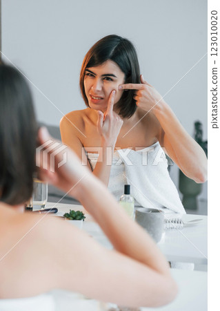 Squeezing the pimple. Young woman is at home. Conception of beauty 123010020