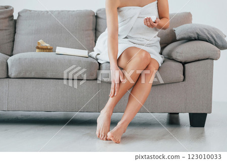 Using cream to clean legs skin. Young woman is at home. Conception of beauty 123010033