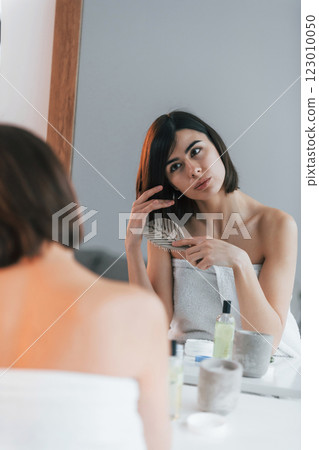 Combing hair. Young woman is at home. Conception of beauty 123010050
