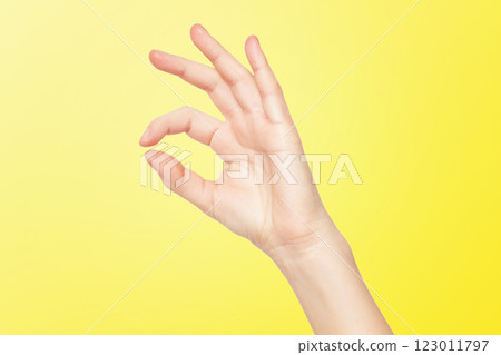 Closeup female hand making OK gesture isolated at yellow background. 123011797