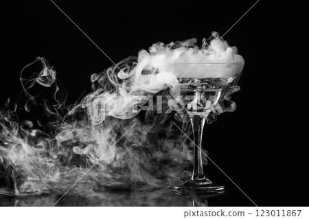 Closeup glass with white fog at dark background. Chemical reaction of dry ice with water. Closeup glass with white fog at dark background. Chemical reaction of dry ice with water. 123011867