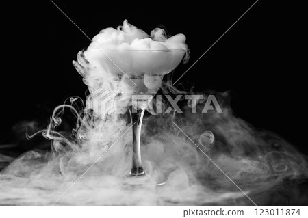 Closeup glass with white fog at dark background. Chemical reaction of dry ice with water. 123011874