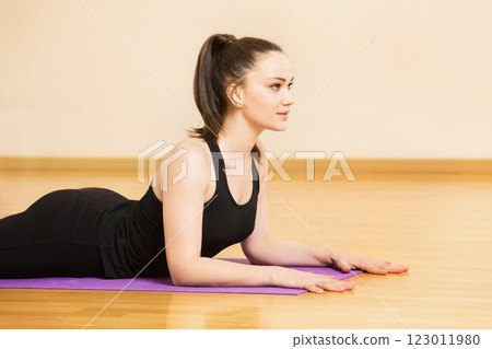 Young woman is making yoga exercises on a mat at gym background. Young woman is making yoga exercises on a mat at gym background. 123011980
