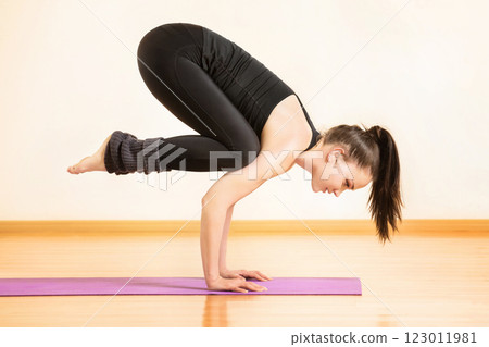 Young woman is practising yoga in bhujapidasana pose at gym background. Young woman is practising yoga in bhujapidasana pose at gym background. 123011981