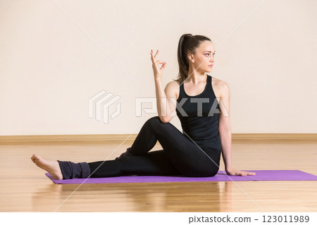 Young woman is practicing yoga in half lord of the fishes pose at gym. Young woman is practicing yoga in half lord of the fishes pose at gym. 123011989