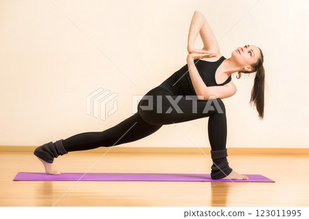 Young woman is practicing anjaneyasana yoga pose at gym background. 123011995