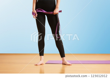 Slim athlete woman is holding trx straps for fitness training at isolated blue background. 123012012