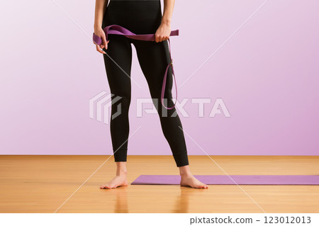 Slim athlete woman is holding trx straps for fitness training at isolated purple background. 123012013