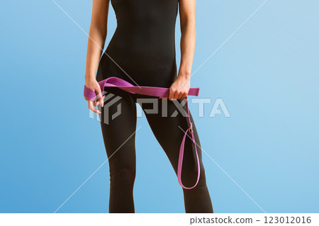 Slim athlete woman is holding trx straps for fitness training at isolated blue background. 123012016