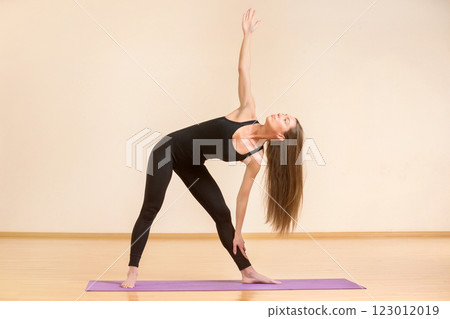 Young woman is making stretching fitness exercises on a a mat at gym. Young woman is making stretching fitness exercises on a a mat at gym. 123012019