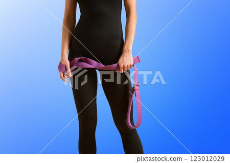 Slim athlete woman is holding trx straps for fitness training at isolated blue background. 123012029