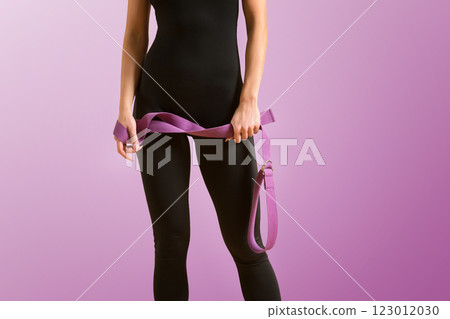 Slim athlete woman is holding trx straps for fitness training at isolated purple background. 123012030