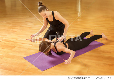 Pilates trainer is teaching young healthy woman at gym. Fitness exercise workout. 123012037