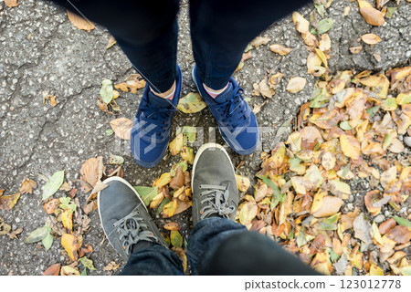 Couple standing amongst dried fall leaves 123012778