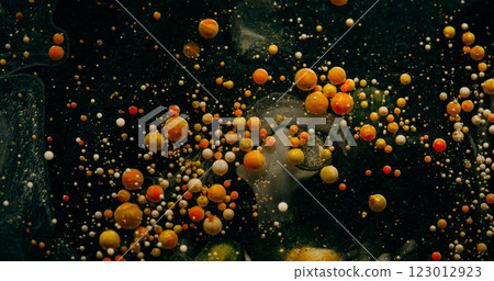 Bubble flow. Paint blob. Colorful drops particles spilling in black water. Orange yellow ball oil pigment splash defocused abstract background. Bubble flow. Paint blob. Colorful drops particles spilling in black water. Orange yellow ball oil pigment splash defocused abstract background. 123012923