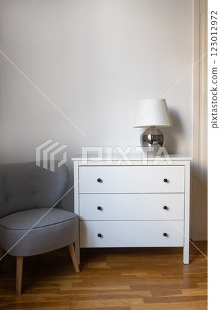 Minimalist interior with white dresser and gray chair 123012972