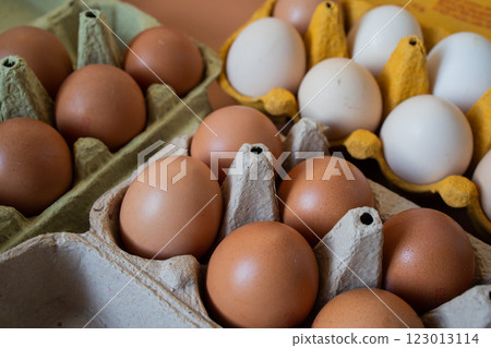 White and brown chicken eggs in multicolored paper cartons White and brown chicken eggs in multicolored paper cartons 123013114