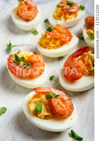 Boiled eggs stuffed with yolk and seasoned with mayonnaise, stuffed eggs with shrimp, on a white wooden chopping board, selective focus, close-up, without people, 123013280