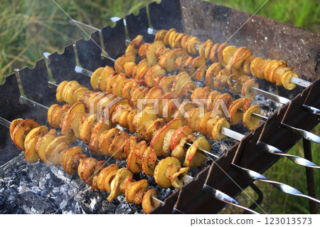 Potato skewers with bacon. Marinated shashlik preparing on barbecue grill over charcoal Potato skewers with bacon. Marinated shashlik preparing on barbecue grill over charcoal 123013573