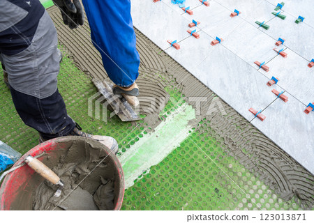 Piastrellista al lavoro installa un nuovo pavimento con le piastrelle. Edilizia. 123013871
