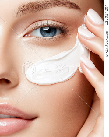Skincare Serenity. Close-up of a woman's face with a focus on eye cream application 123014204