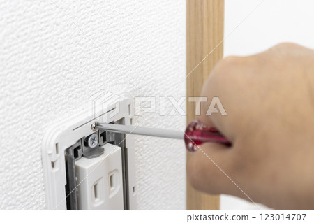 一個電源插座,蓋子被取下,一名男子的手拿著螺絲刀 一個電源插座,蓋子被取下,一名男子的手拿著螺絲刀 123014707