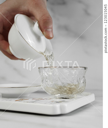 An Elegant Teapot Pouring Aromatic Tea into a Glass Cup, Celebrating Serenity and Tradition 123015045