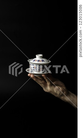 An Elegant Handheld Teacup Displayed Against a Dark, Striking Background for Visual Appeal 123015086
