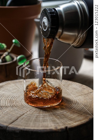 Carefully pouring a refreshing beverage into a glass sitting on a rustic wooden surface 123015222
