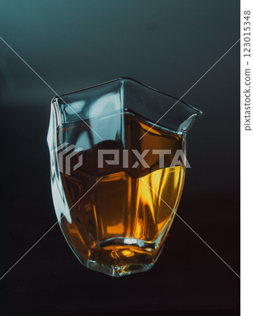 An Elegant Glass Pitcher Filled with Amber Liquid Set Against a Dark Background for Contrast 123015348