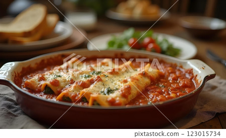Plate of stuffed manicotti pasta with tomato sauce, parmesan, and fresh basil garnish 123015734