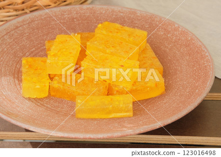 Marmalade in a plate in garden table. Sweet orange dessert for holiday. Homemade fruit candies. 123016498