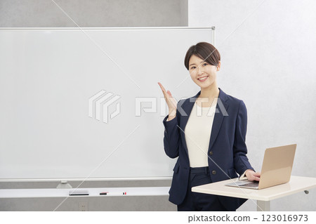 Businesswoman pointing at whiteboard with palm of hand in conference room 123016973