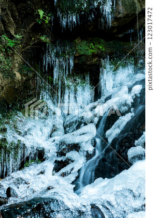 The ice covering the frozen waterfall and the water flowing underneath The ice covering the frozen waterfall and the water flowing underneath 123017472