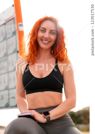 Confident sporty woman smiling while sitting at 123017530