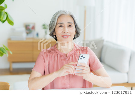Senior woman operating a smartphone in the living room Senior woman operating a smartphone in the living room 123017931