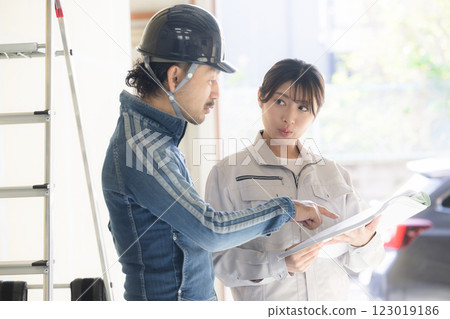 A man in denim work clothes and a woman in work clothes holding a blueprint Checking the site 123019186