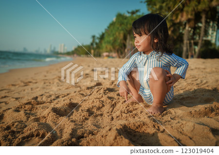 toddler baby girl sitting on sea beach in Pattaya, Thailand 123019404