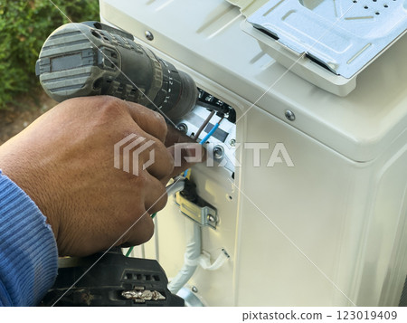 worker connects electric wires to installation of air conditioner 123019409