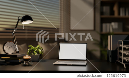 A modern office features a laptop with a white screen mockup and decorative items on a black desk. A modern office features a laptop with a white screen mockup and decorative items on a black desk. 123019973