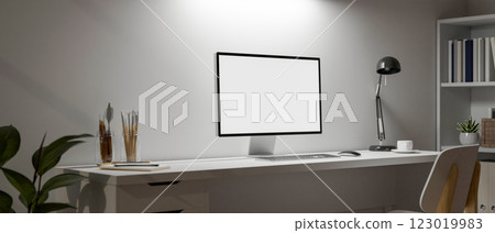 A minimalist white office features a computer set on a white desk against a white wall. 123019983