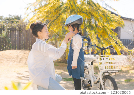 Mom and girl putting a helmet on Mom and girl putting a helmet on 123020065