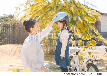 Mom and girl putting a helmet on Mom and girl putting a helmet on 123020066