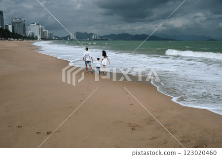 back of happy family with a child son running along the beach by sea in summer back of happy family with a child son running along the beach by sea in summer 123020460