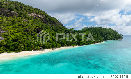 Green hillside meets turquoise waters, with a white sand beach stretching along the coast. Therese. Seychelles, Mahe. 123021156